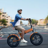 Hombre conduciendo una bicicleta eléctrica plegable ENGWE EP-2 Boost naranja por una calle urbana, equipada con neumáticos anchos, suspensión delantera, guardabarros y portaequipajes trasero.